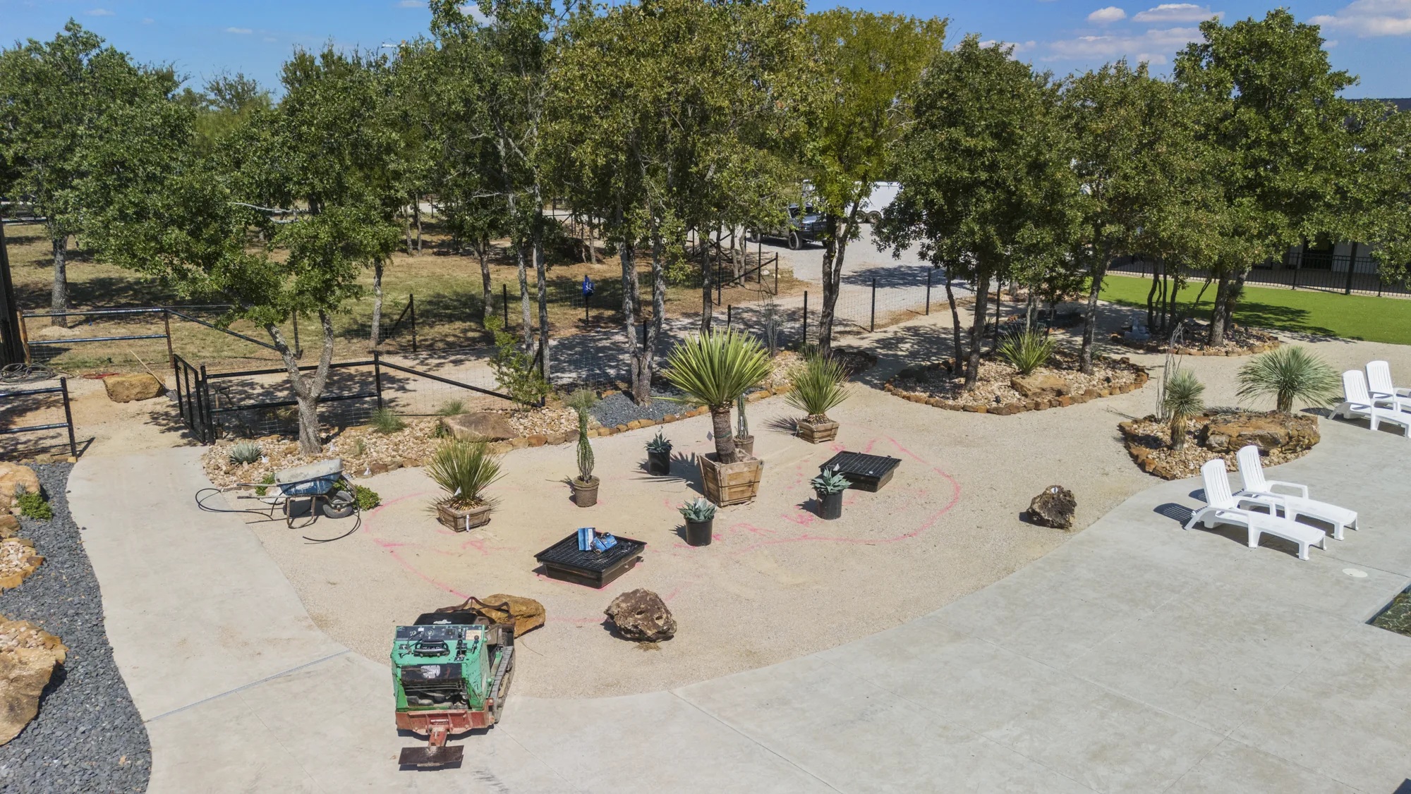 Aerial view of a decomposed granite yard with staged specimens, seating and live oaks