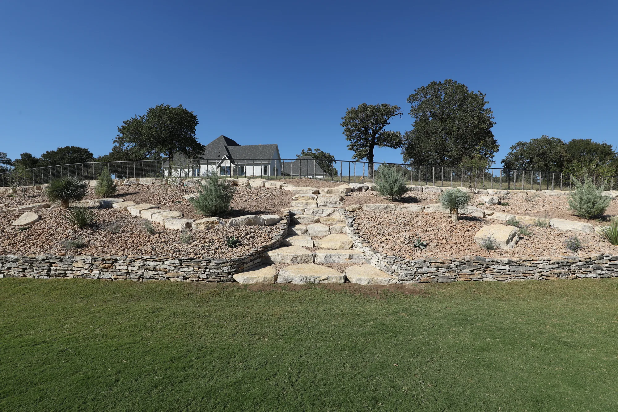 Limestone retaining terraces stepping down to a turf lawn, hills beyond