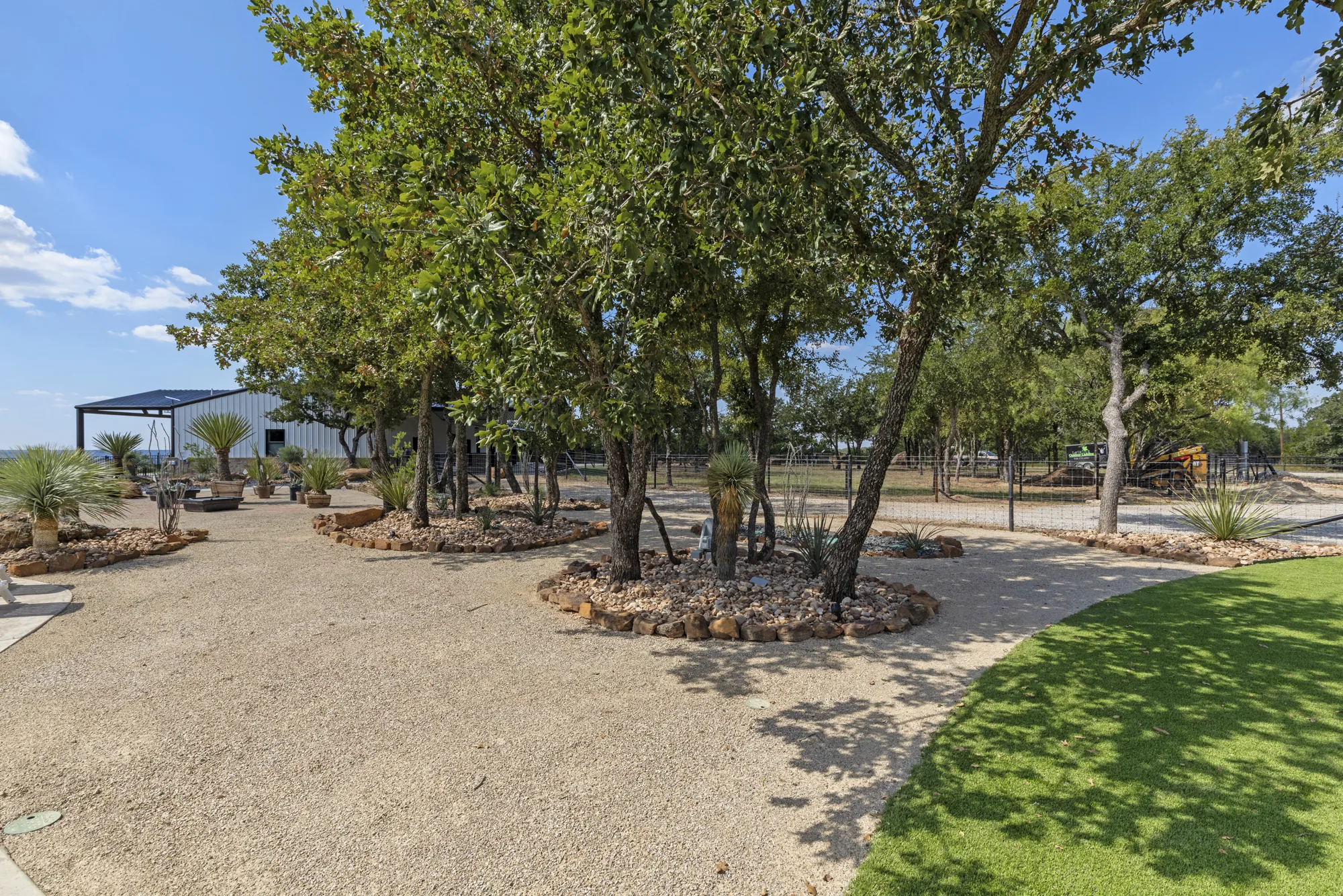 A preserved oak motte with boulder-edged planting beds in decomposed granite