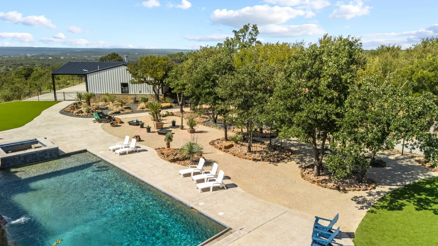 Stamped concrete patio and spa deck edged with xeriscape beds and mature live oaks