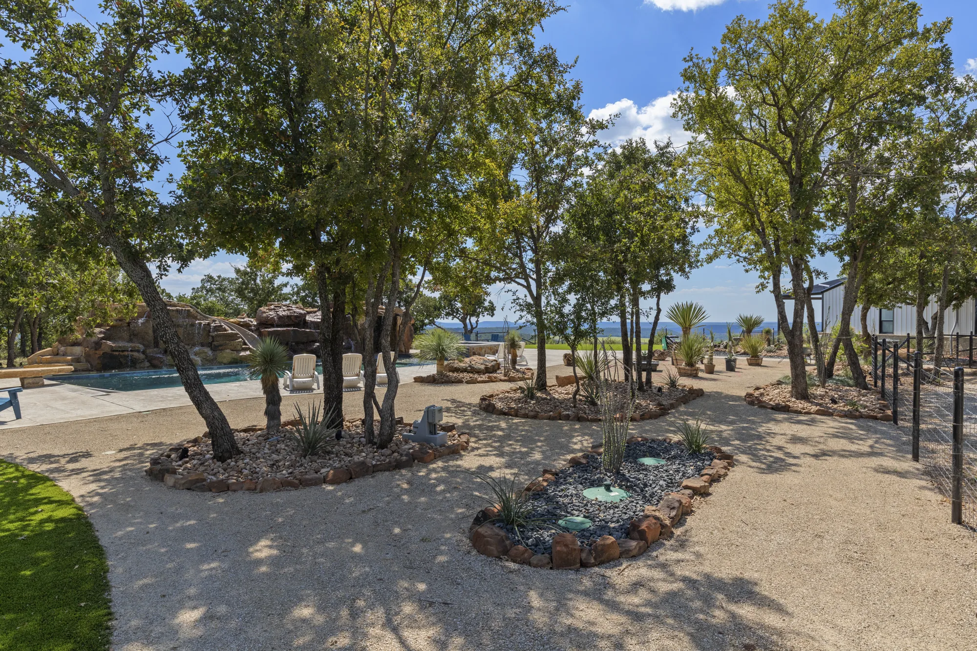 Boulder-edged planting islands with agave and yucca beneath a live oak canopy