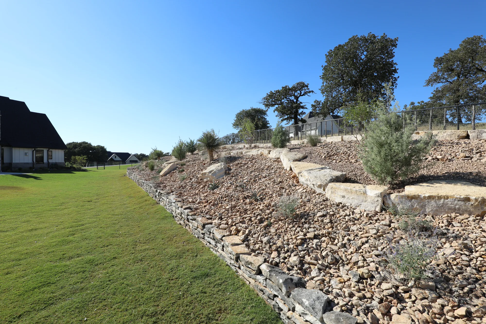 Stone terracing with a river rock drainage bed carrying water away from the house
