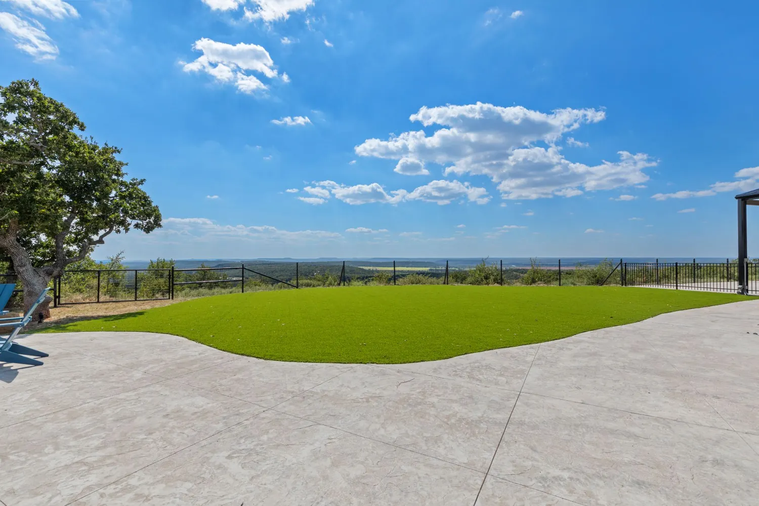 Synthetic turf lawn edged in stamped concrete, opening to a hillside view