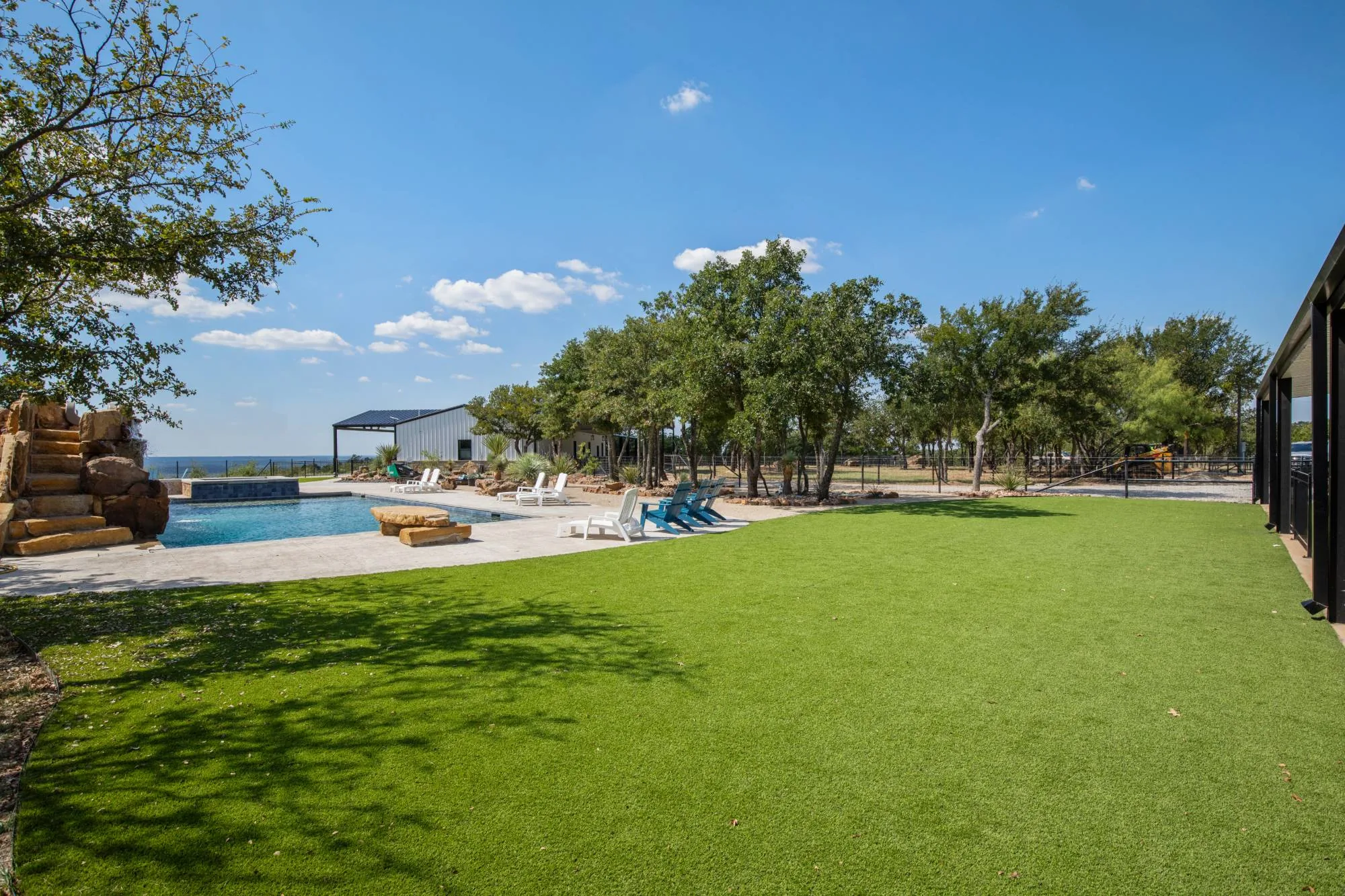 A turf lawn meeting a pool with a stacked-stone waterfall feature