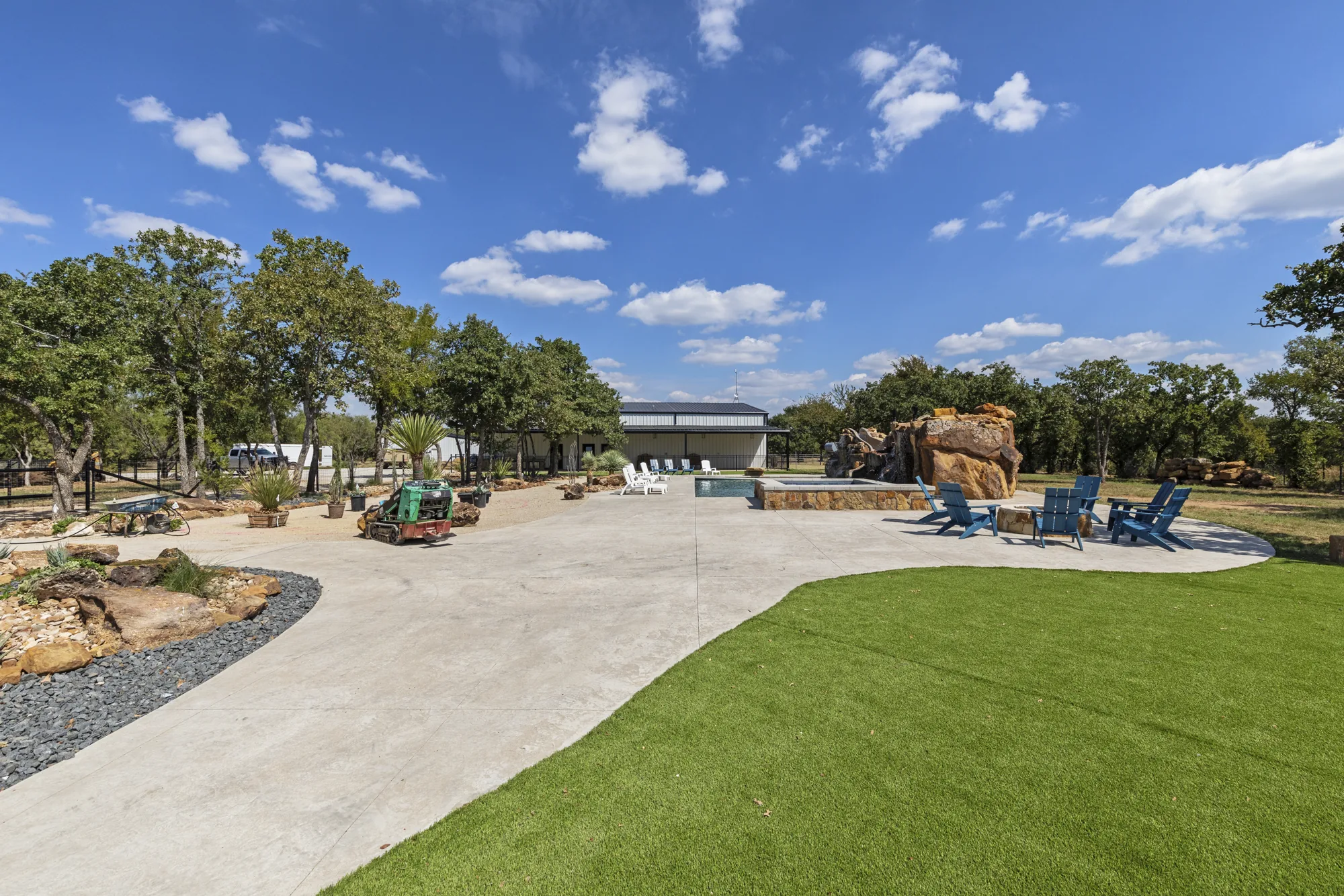 A pool terrace with Adirondack chairs, a boulder water feature and decomposed granite paths