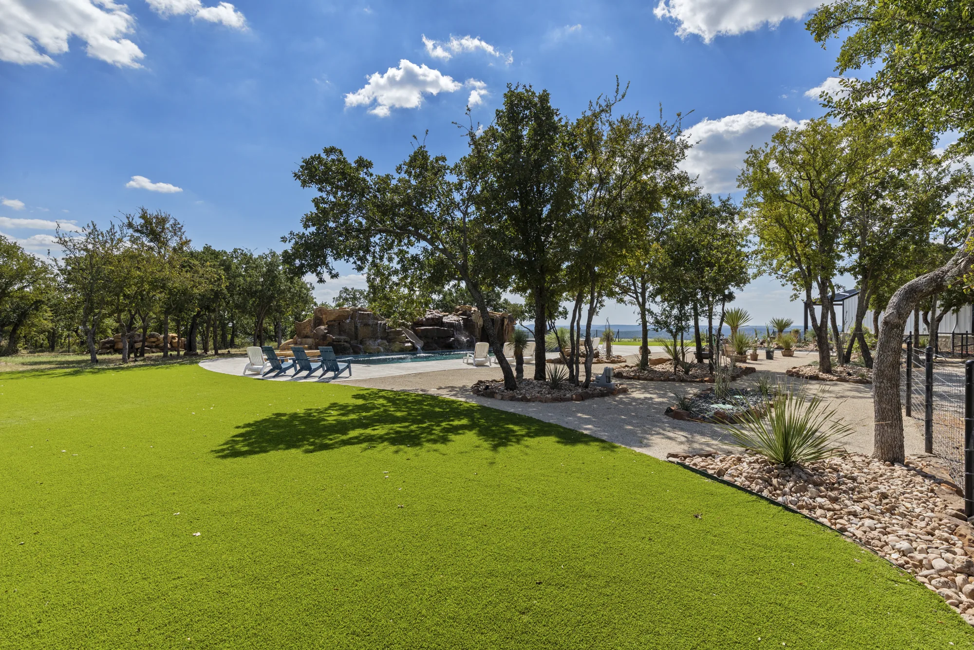 A curved turf lawn edge meeting decomposed granite paths beneath live oaks