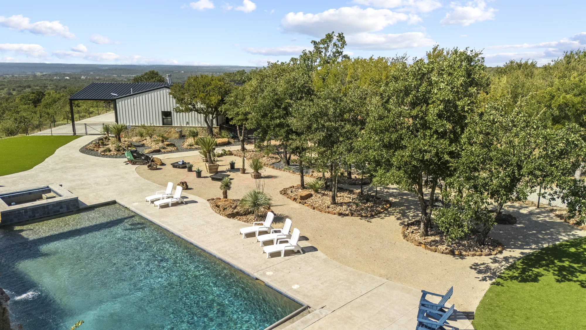 Aerial view of a pool and artificial turf lawn framed by mature live oaks