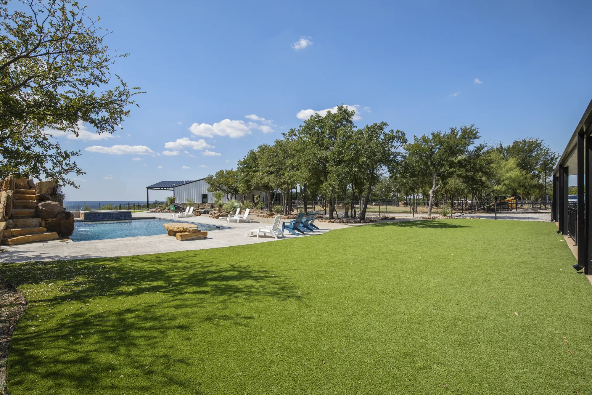 Artificial turf lawn running to a pool surround under mature live oaks