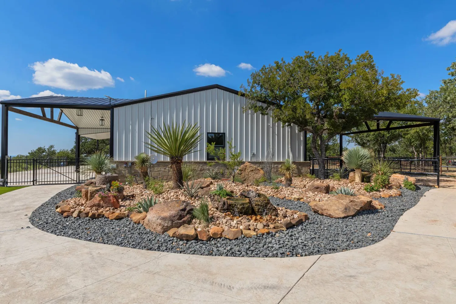 Xeriscape island bed with native boulders, a recirculating water feature, beaked yucca and agave