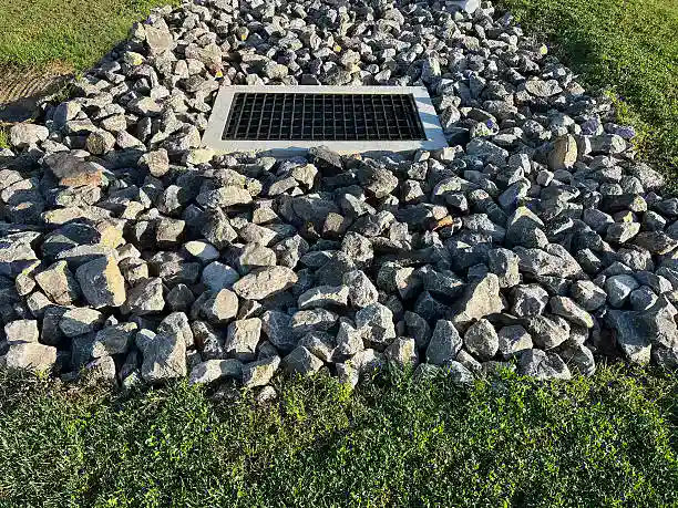 Storm drain surrounded by rocks and grass.